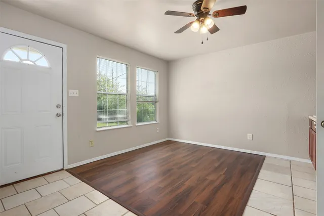 a view of an empty room with window and chandelier fan