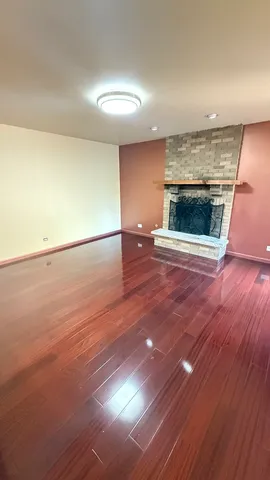 an empty room with wooden floor fireplace and windows