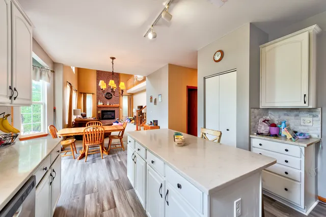 a room with stainless steel appliances kitchen island granite countertop a table chairs and a refrigerator