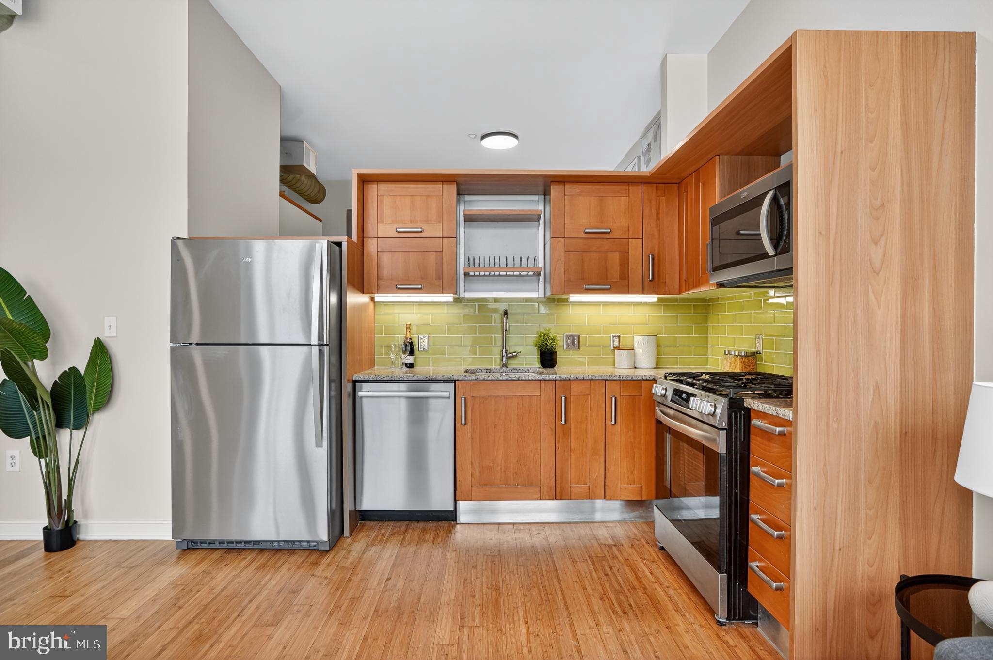 1390 V Street Northwest, Unit 306 Washington, DC 20009 - Photo 5 of 19 a kitchen with stainless steel appliances granite countertop a refrigerator a stove a sink and a wooden floor