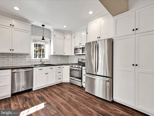 a kitchen with granite countertop stainless steel appliances a refrigerator sink and cabinets