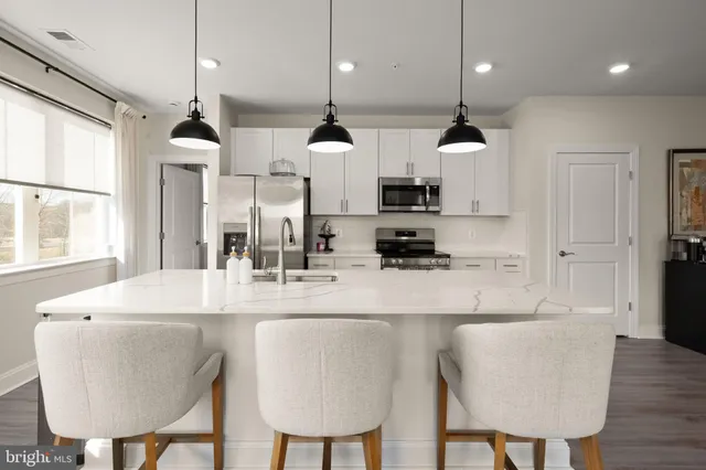 a kitchen with stainless steel appliances kitchen island granite countertop a table chairs and a refrigerator