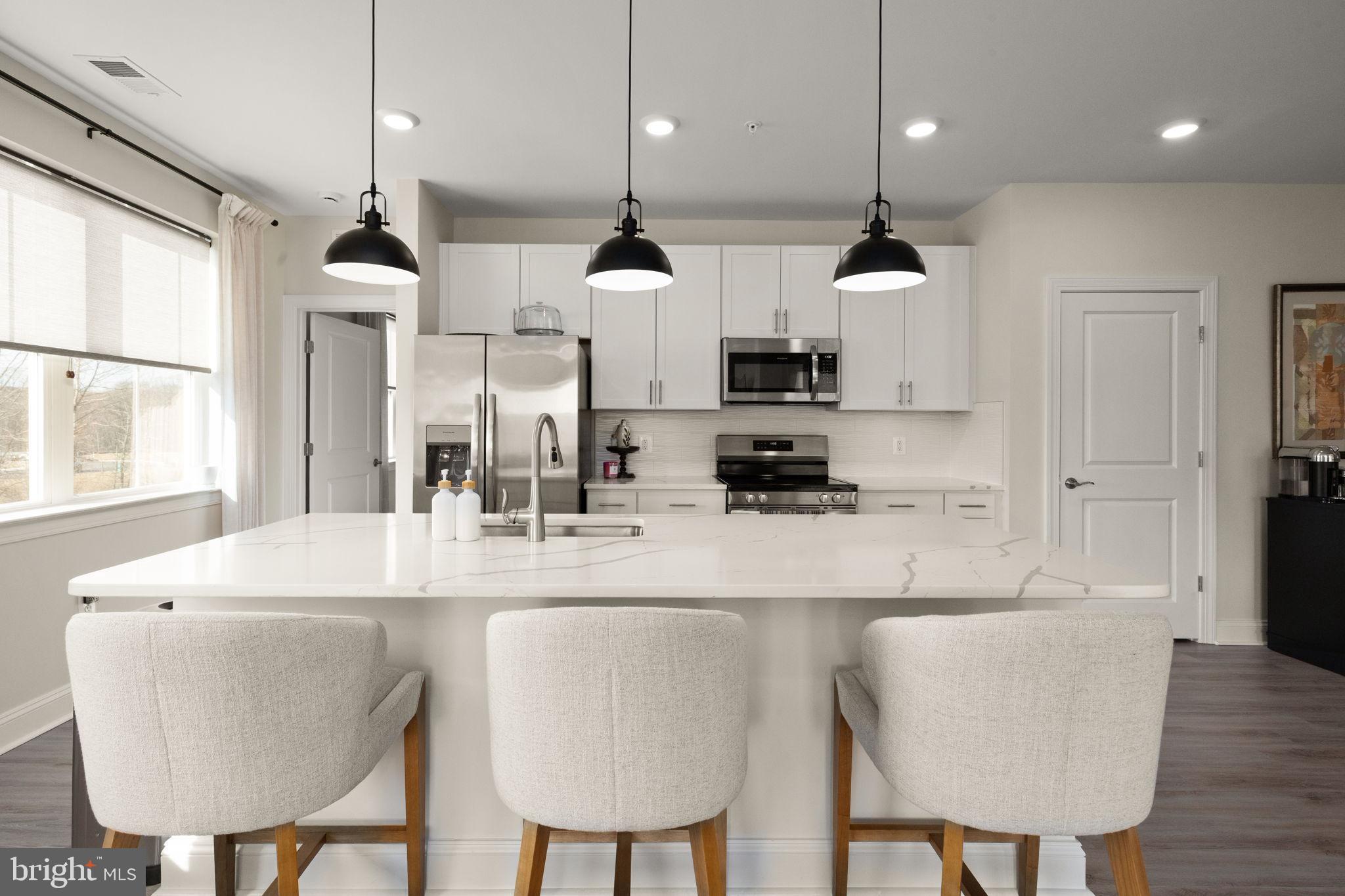 406 Bold Ruler Court, Unit 207 Havre de Grace, MD 21078 - Photo 12 of 57 a kitchen with stainless steel appliances kitchen island granite countertop a table chairs and a refrigerator