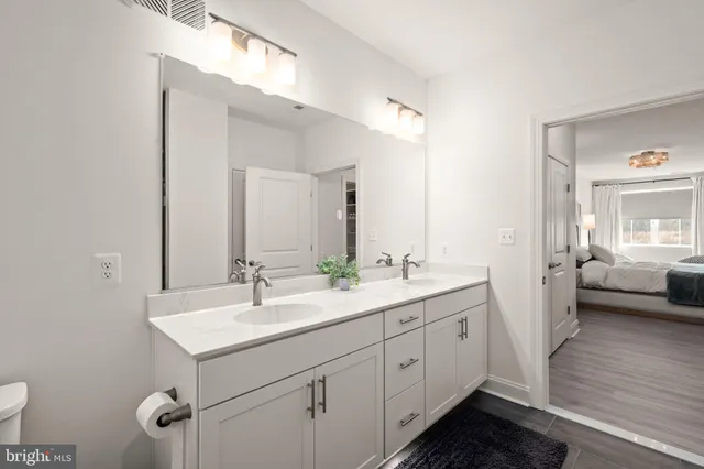 a en suite bathroom with a double vanity sink a mirror and a toilet