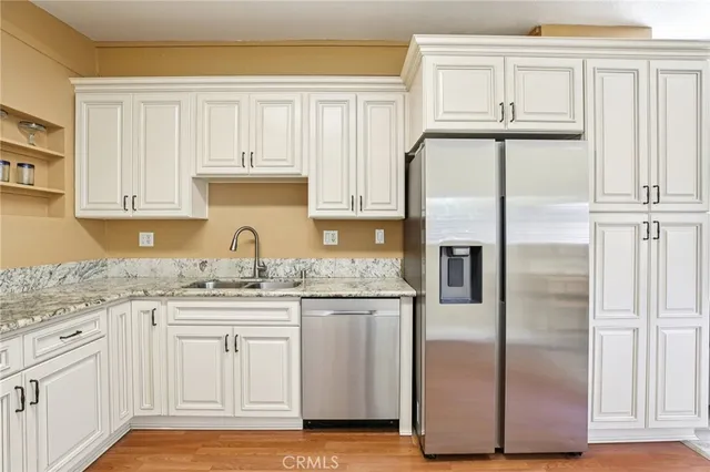 a kitchen with granite countertop a refrigerator sink and cabinets