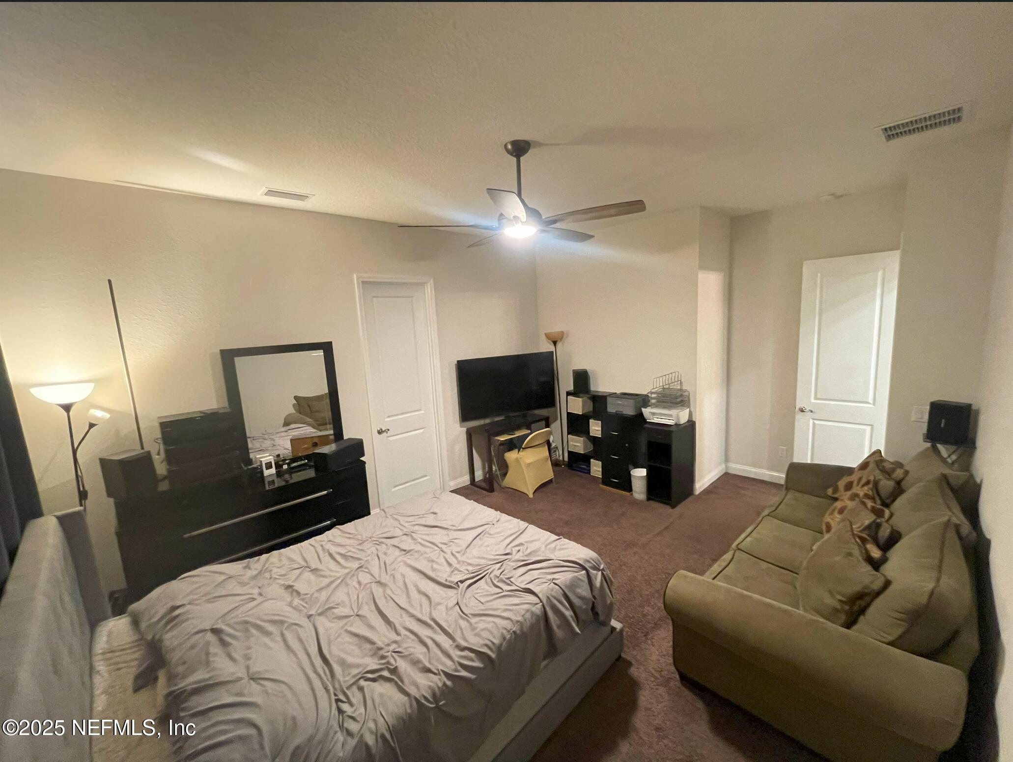 2489 Caprera Circle Jacksonville, FL 32246 - Photo 13 of 30 a bed room with a bed a couch and a chandelier
