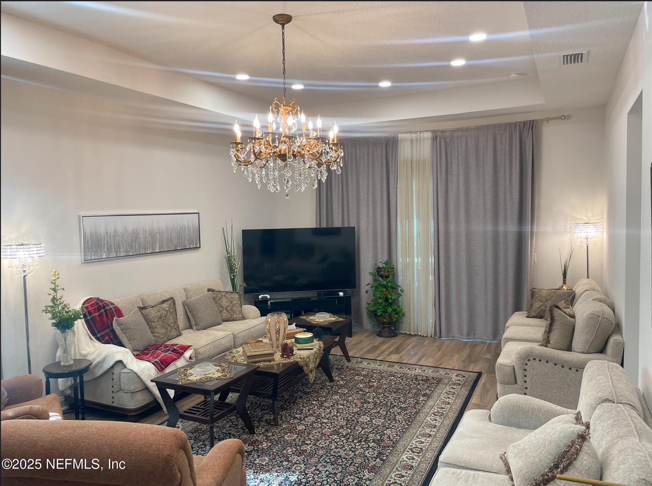 2489 Caprera Circle Jacksonville, FL 32246 - Photo 8 of 30 a living room with furniture a chandelier and a flat screen tv