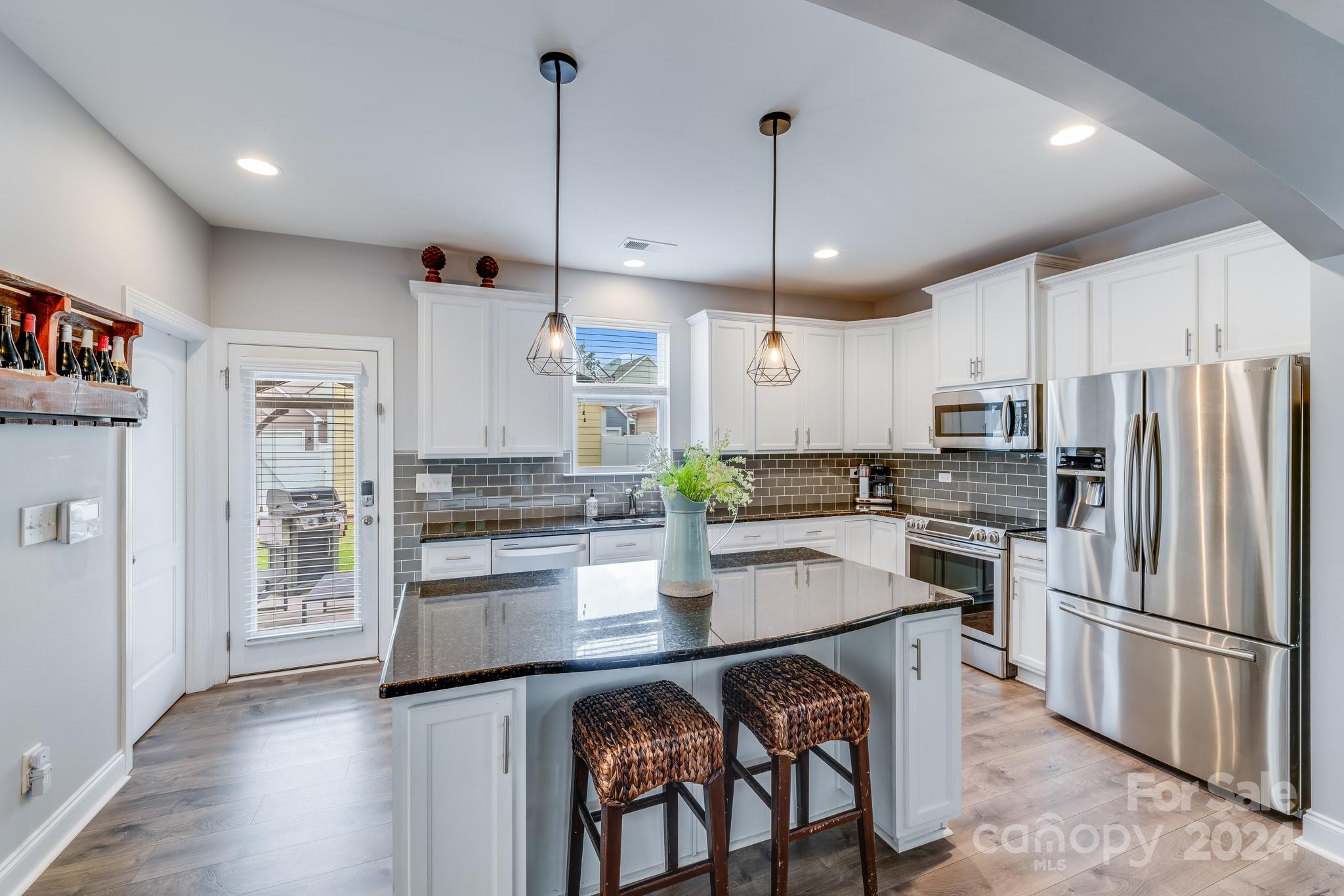 a kitchen with stainless steel appliances granite countertop a refrigerator a stove a sink dishwasher a refrigerator and a dining table with wooden floor
