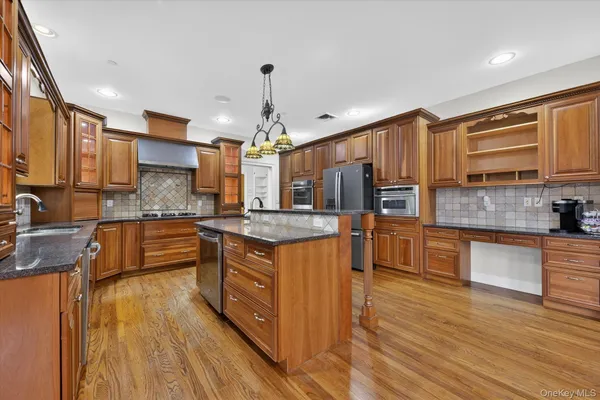a kitchen with granite countertop a stove a sink dishwasher and a refrigerator with wooden floor