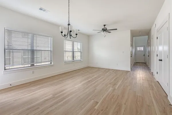 a view of an empty room with a window and wooden floor