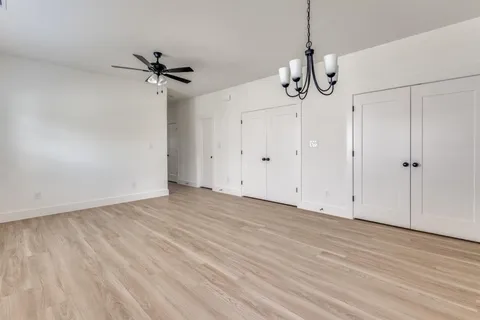 a view of empty room with wooden floor and ceiling fan