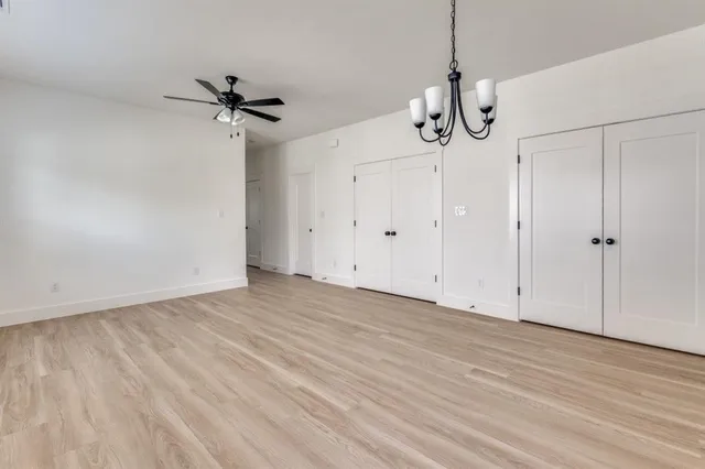 a view of empty room with wooden floor and ceiling fan