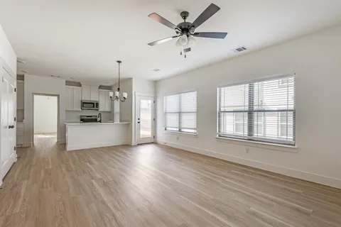 a view of an empty room with window and wooden floor