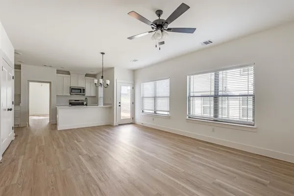 a view of an empty room with window and wooden floor