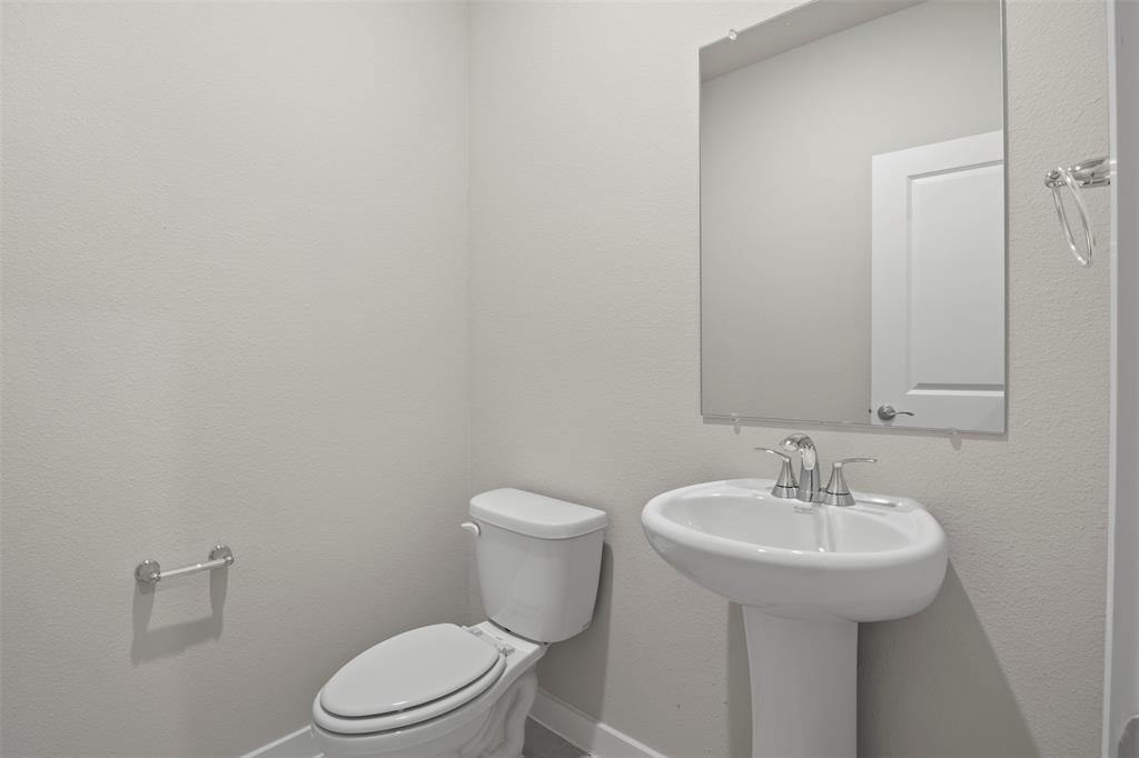 2220 Currents Road Princeton, TX 75407 - Photo 16 of 31 Pedestal sink with chrome fixtures, wall-mounted mirror, and white toilet