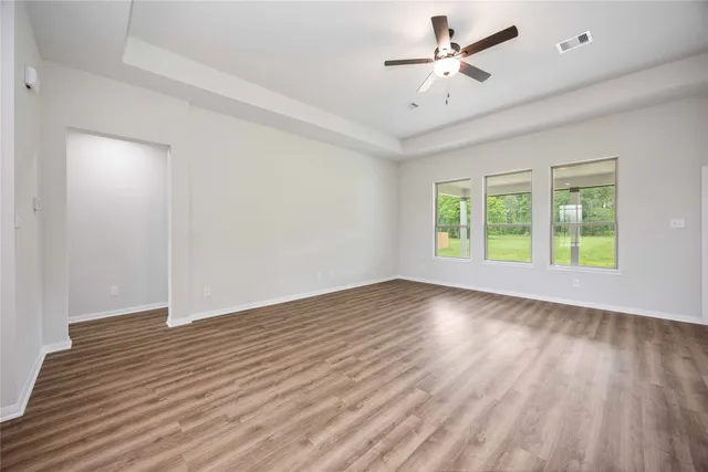 an empty room with wooden floor and windows