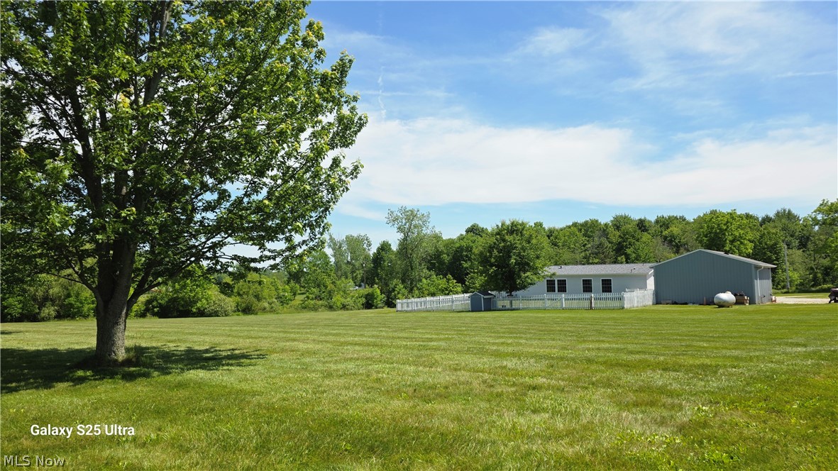 294 Twp 150 Road Sullivan, OH 44880 - Photo 36 of 39 Expansive green lawn with a mature shade tree, white picket fencing, and a detached outbuilding