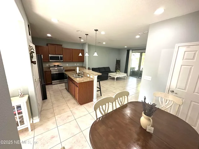 a kitchen with stainless steel appliances kitchen island granite countertop a refrigerator a stove a sink dishwasher with a dining table and chair
