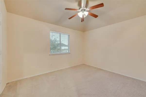 an empty room with a window and a fan
