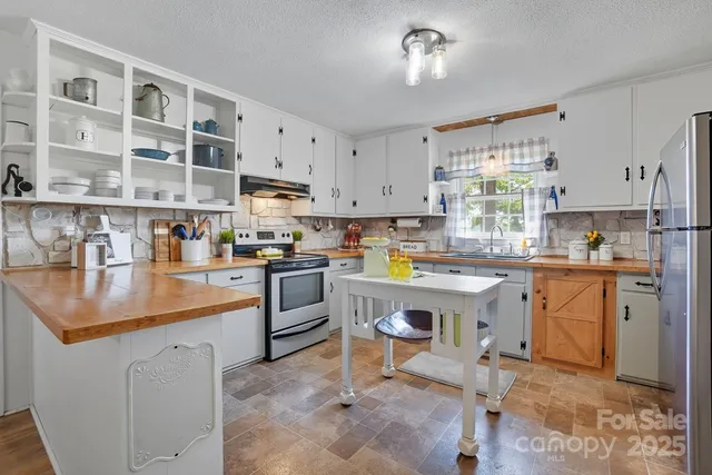 a kitchen with stainless steel appliances granite countertop a refrigerator a stove and a sink