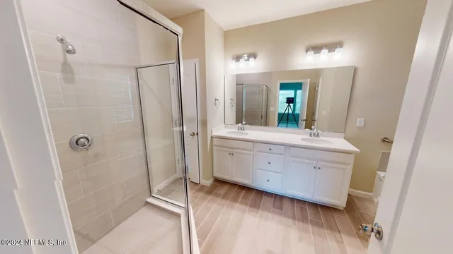 a bathroom with a double vanity sink large mirror and a bathtub