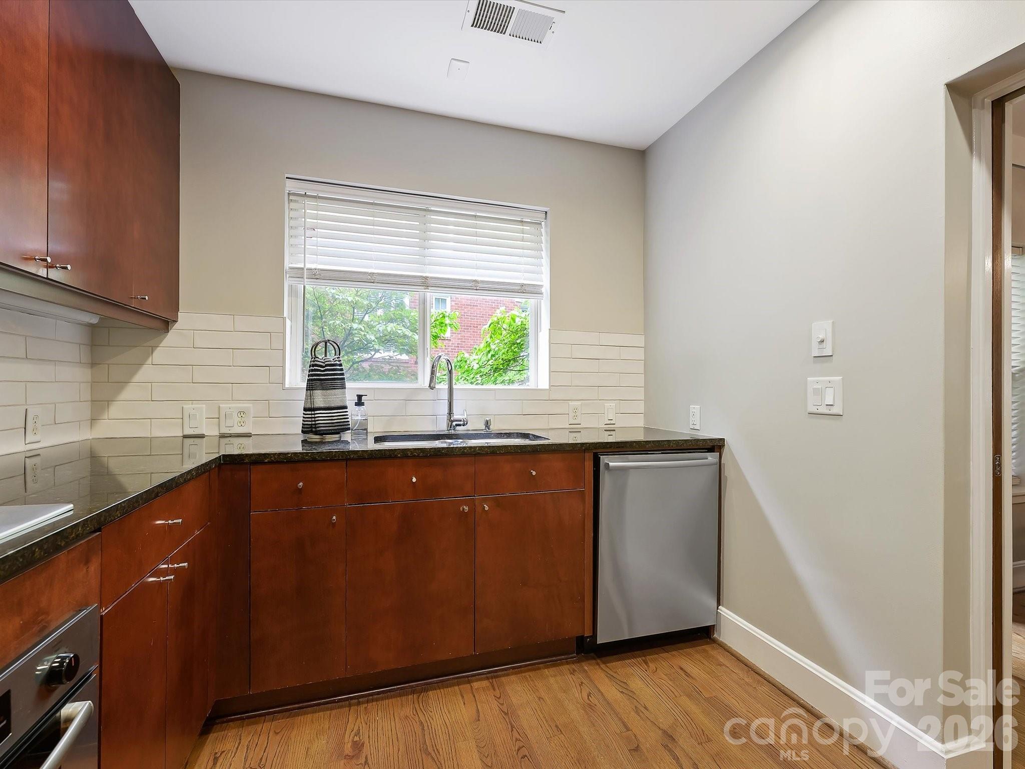 420 Queens Road Charlotte, NC 28207 - Photo 17 of 35 a kitchen with granite countertop wooden cabinets a sink and a window