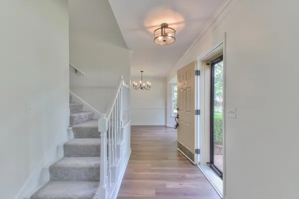 an empty room with chandelier fan and windows