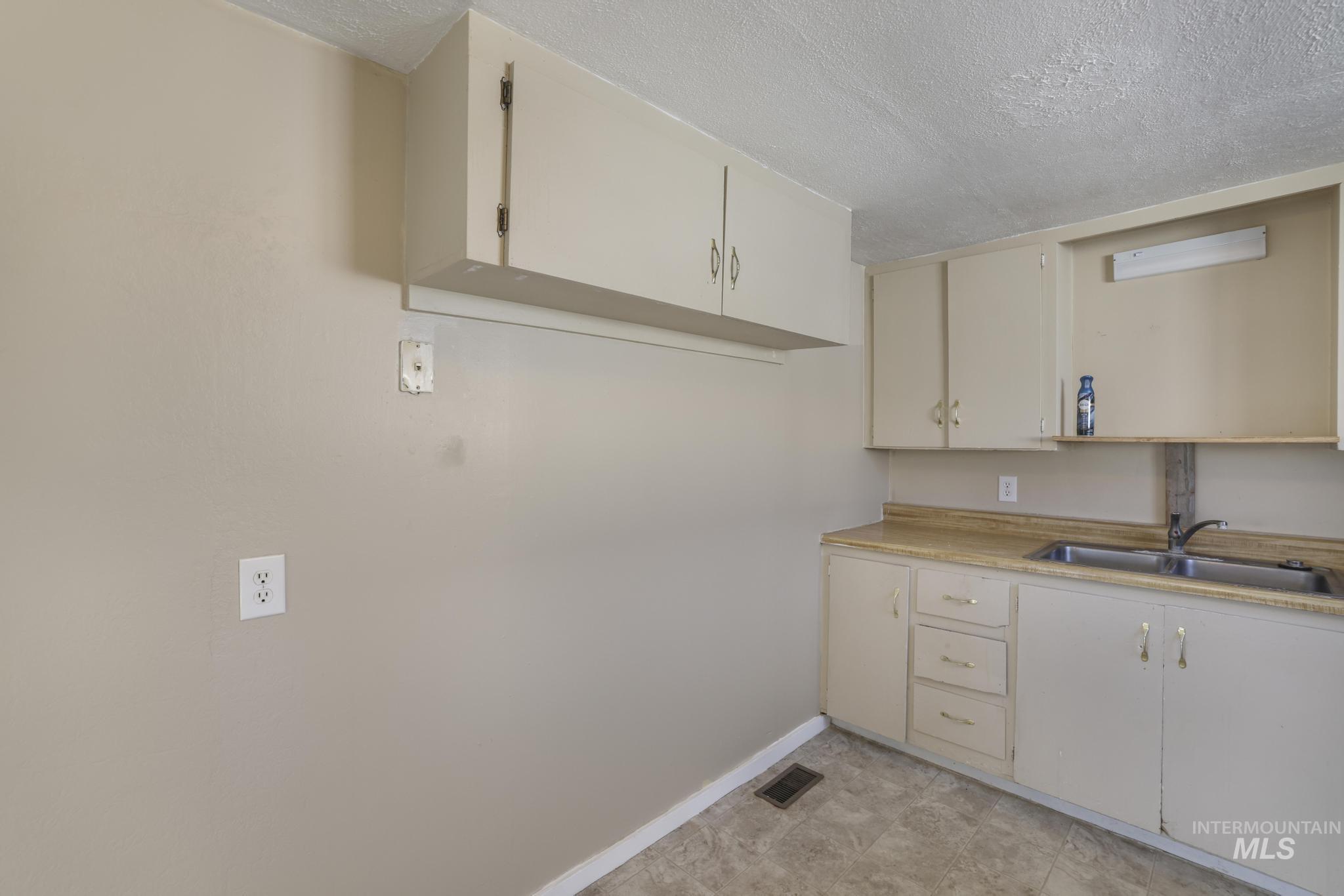 525 Adams Street Twin Falls, ID 83301 - Photo 12 of 31 Kitchen featuring a textured ceiling, light countertops, and cream cabinetry