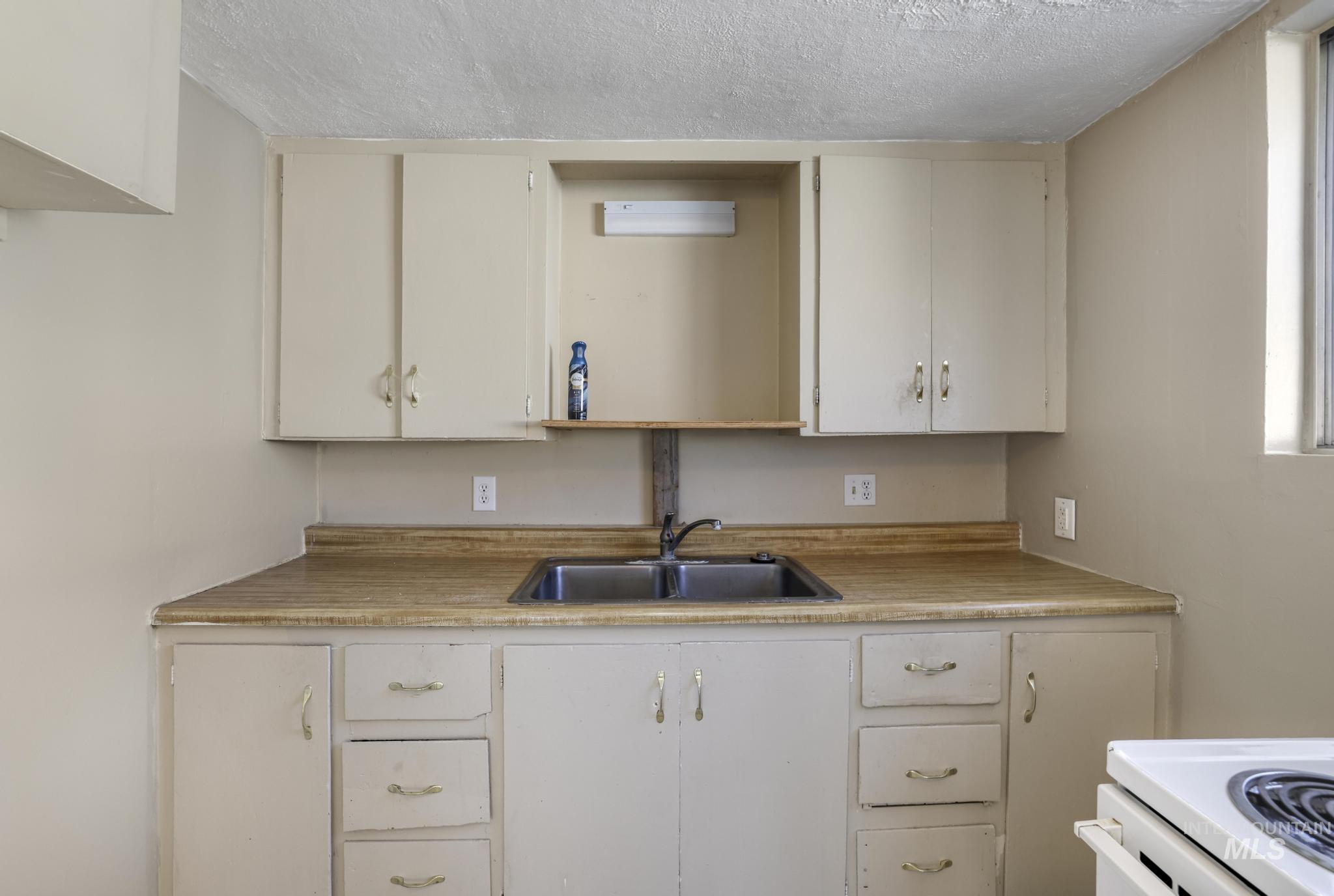 525 Adams Street Twin Falls, ID 83301 - Photo 13 of 31 Kitchen with light countertops, a textured ceiling, and white cabinets