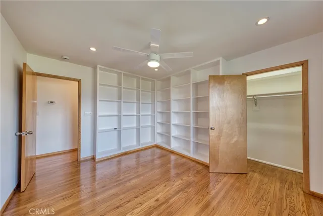 an empty room with wooden floor closet and windows