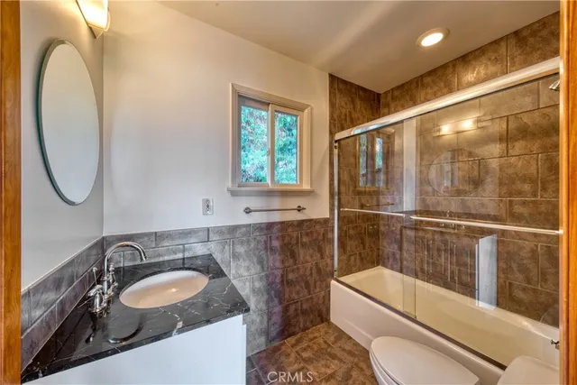 a bathroom with a granite countertop sink a toilet and bathtub