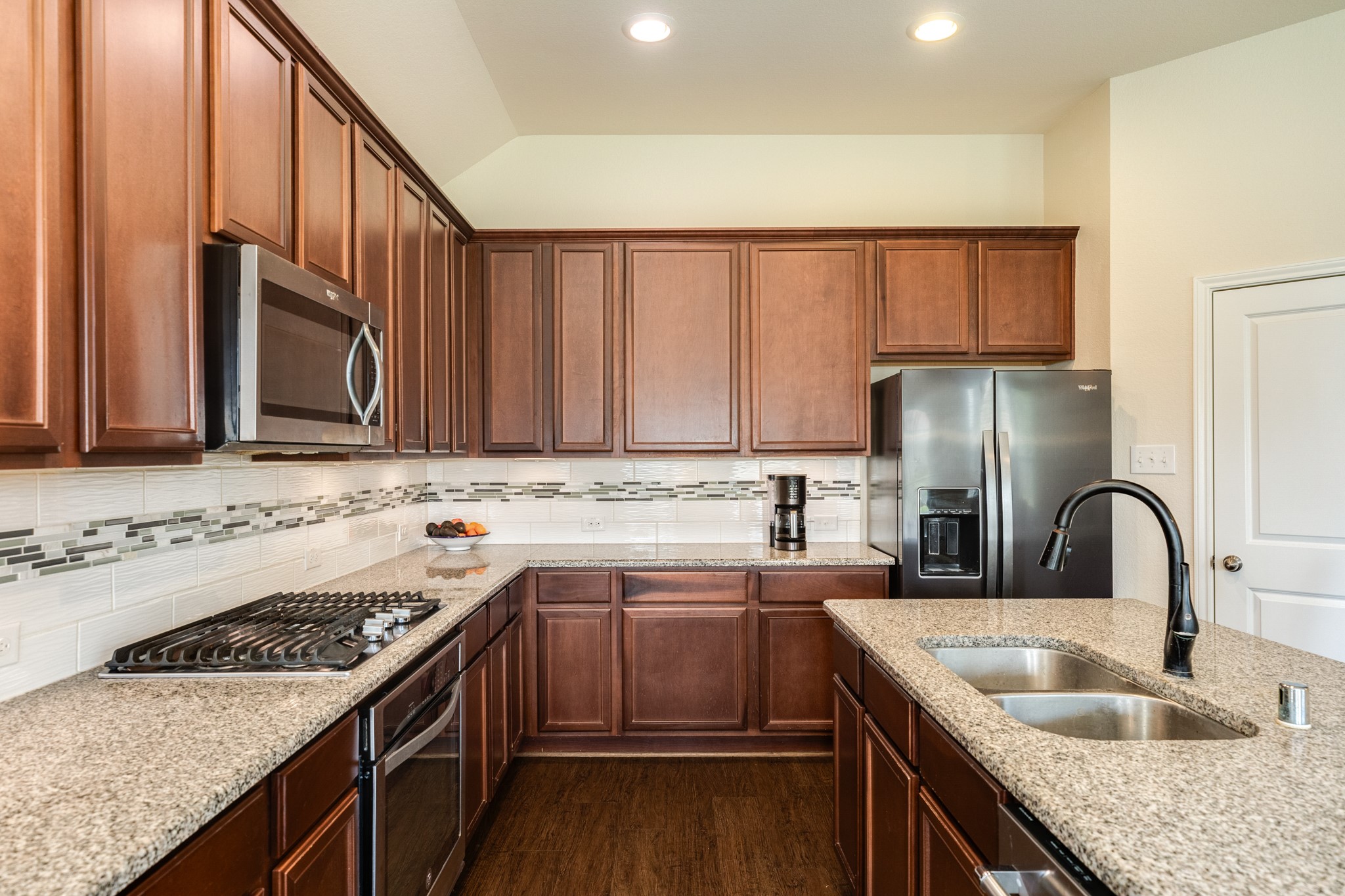 3519 Bay Drive Rosharon, TX 77583 - Photo 15 of 49 Modern kitchen featuring a sleek gas range top and a spacious double-basin sink accented with contemporary, high-end hardware for a polished, functional workspace.