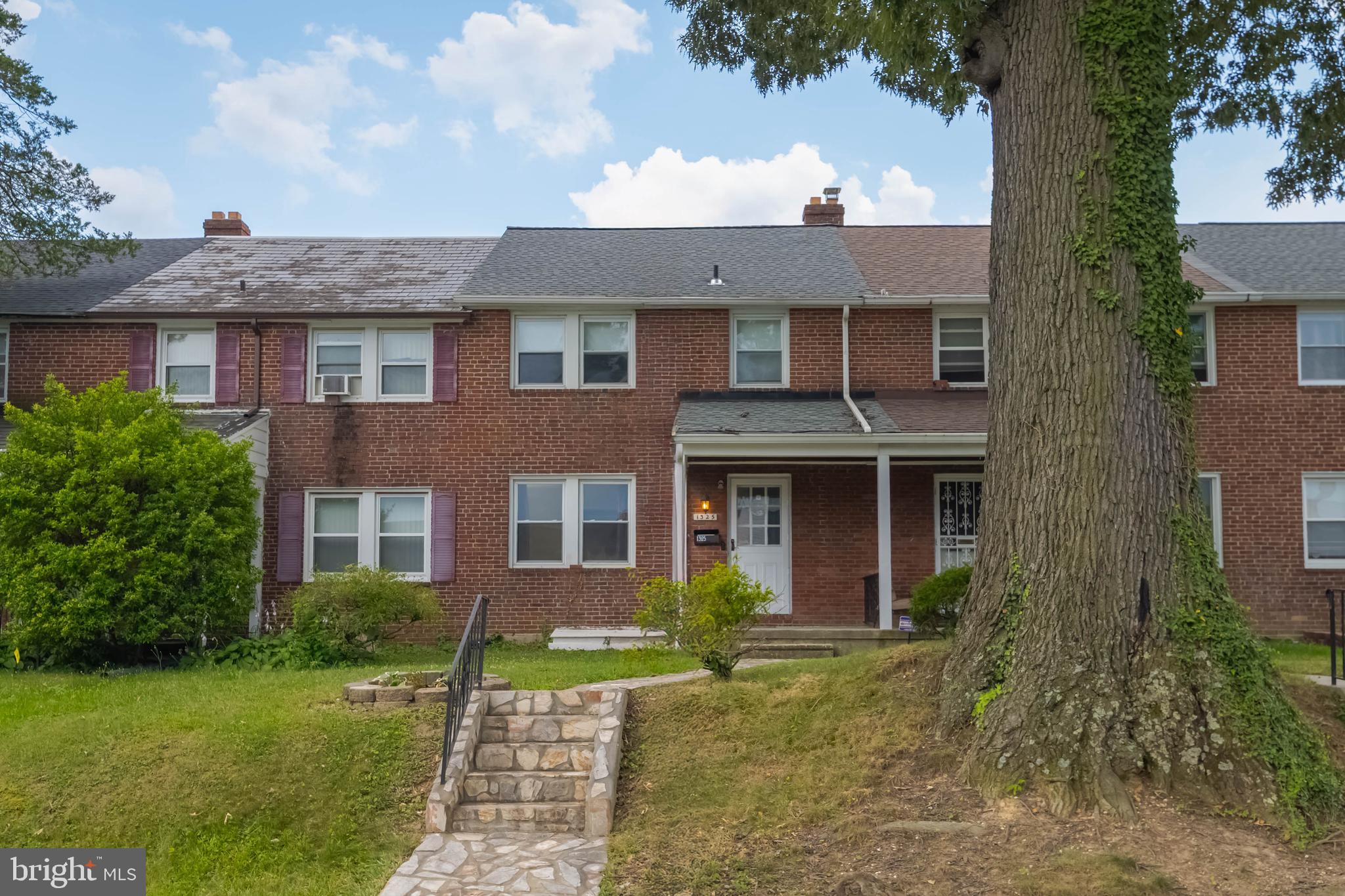 1325 Crofton Road Baltimore, MD 21239 - Photo 1 of 25 a view of a brick house with a yard and large tree
