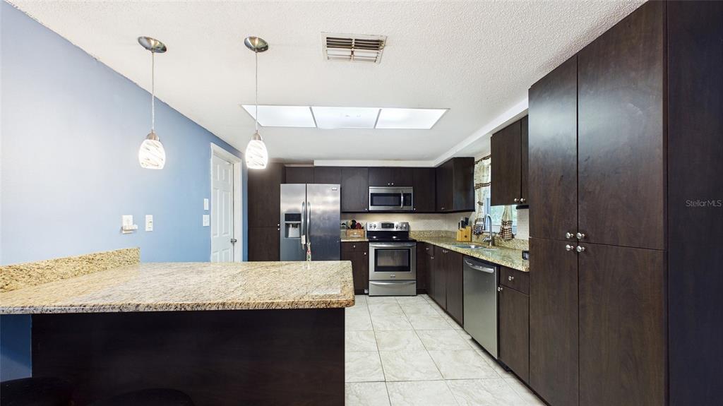 8840 Carmen Lane Port Richey, FL 34668 - Photo 11 of 49 a kitchen with stainless steel appliances granite countertop a sink and cabinets
