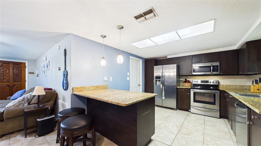 8840 Carmen Lane Port Richey, FL 34668 - Photo 13 of 49 a kitchen with stainless steel appliances granite countertop a stove refrigerator sink and cabinets