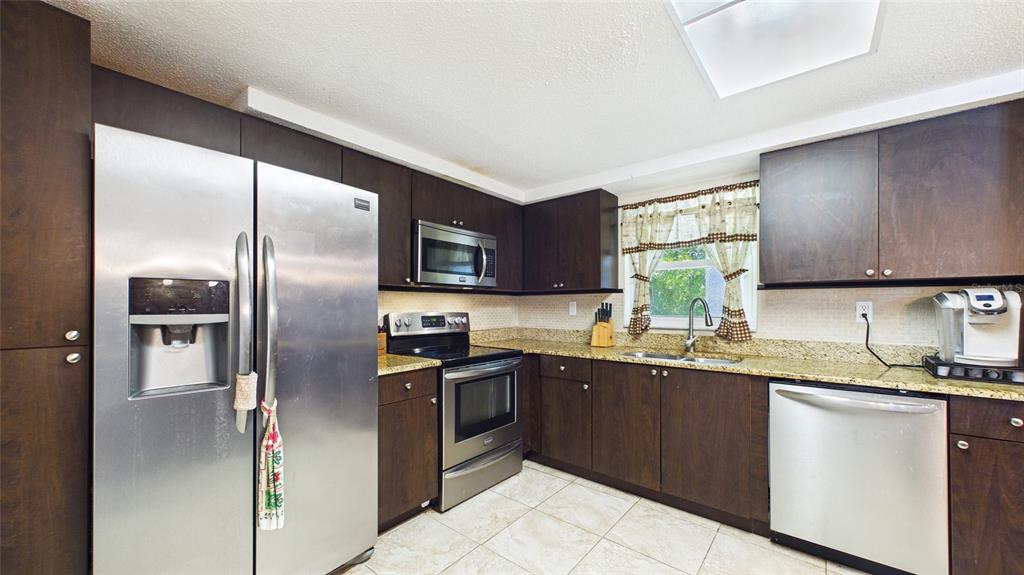 8840 Carmen Lane Port Richey, FL 34668 - Photo 14 of 49 a kitchen with stainless steel appliances granite countertop a sink stove and refrigerator