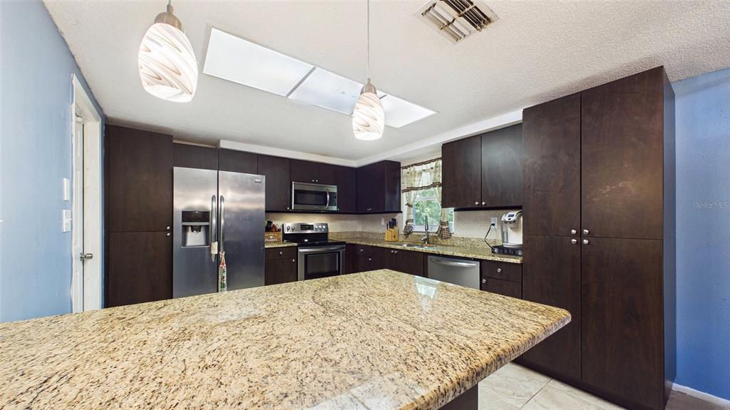 8840 Carmen Lane Port Richey, FL 34668 - Photo 16 of 49 a kitchen with stainless steel appliances kitchen island granite countertop a refrigerator stove top oven and sink