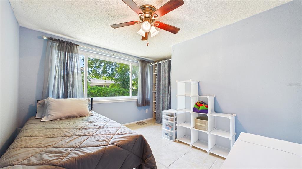 8840 Carmen Lane Port Richey, FL 34668 - Photo 19 of 49 a bedroom with a bed a chandelier and a window