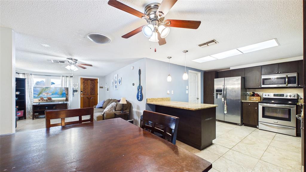 8840 Carmen Lane Port Richey, FL 34668 - Photo 10 of 49 a kitchen with kitchen island a stove a counter top space appliances and a ceiling fan