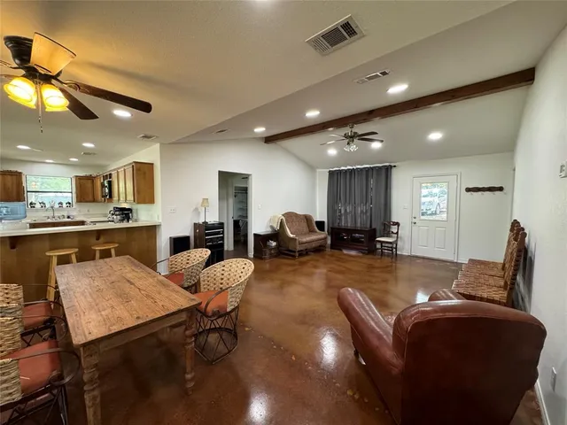 a living room with furniture kitchen view and a wooden floor