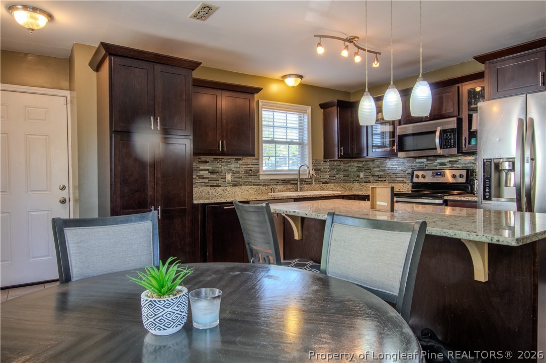 1629 Mattie Road Sanford, NC 27332 - Photo 7 of 29 a kitchen with stainless steel appliances kitchen island granite countertop a refrigerator a stove a sink and a dining table with wooden floor