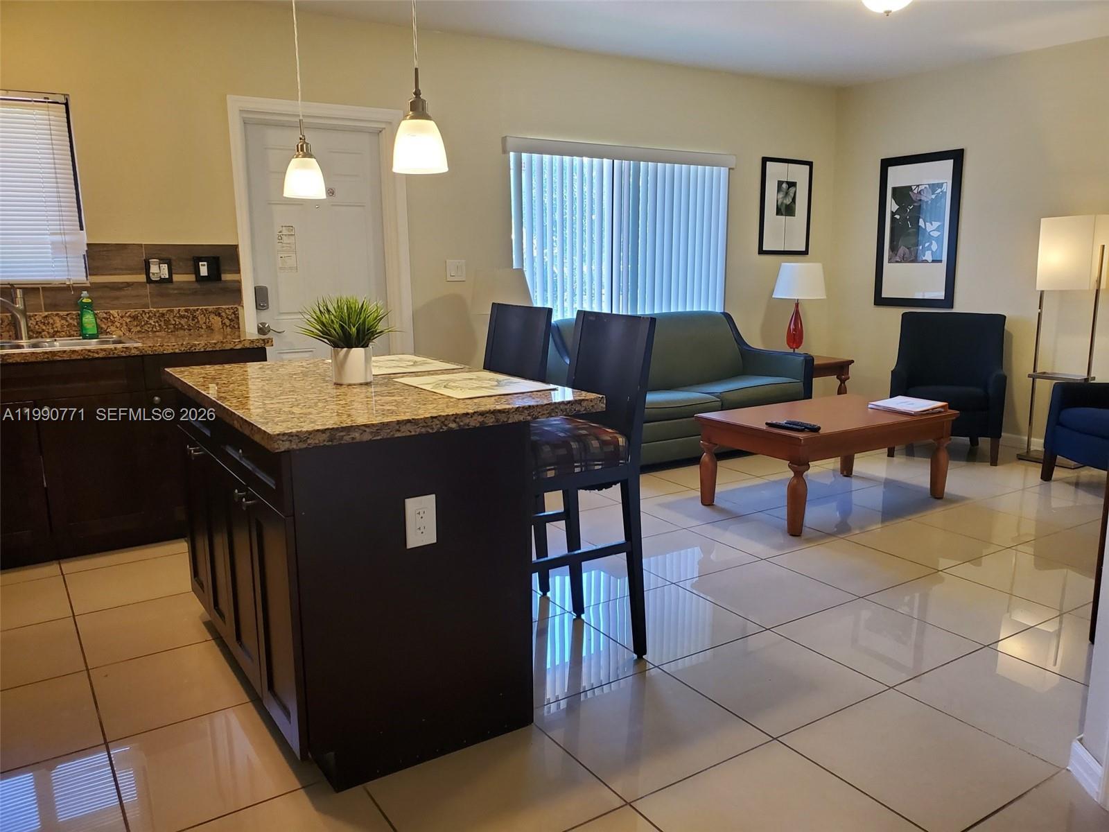 2015 Funston Street, Unit 2 Hollywood, FL 33020 - Photo 10 of 19 a living room with stainless steel appliances kitchen island granite countertop a table chairs and a refrigerator