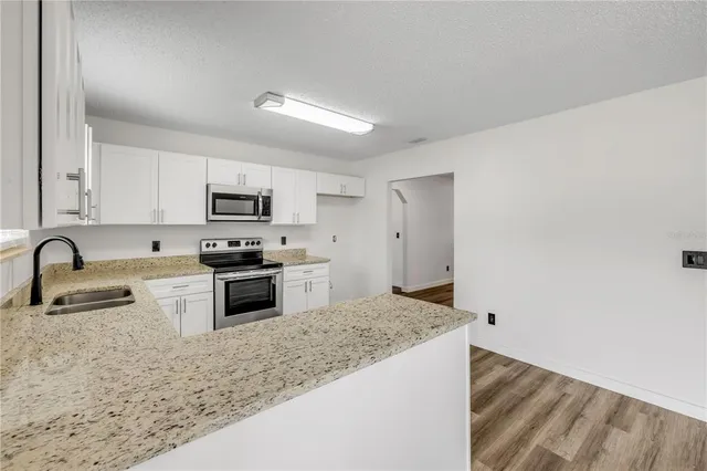 a kitchen with granite countertop a sink a stove top oven and refrigerator