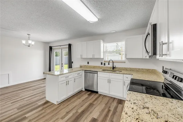 a large kitchen with granite countertop a sink white cabinets and wooden floor