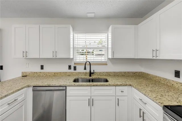 a kitchen with granite countertop white cabinets white appliances and a sink
