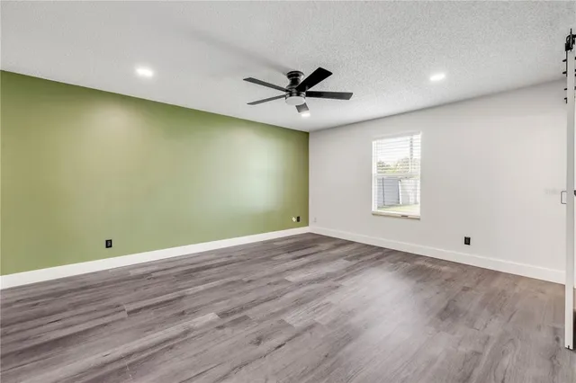 an empty room with wooden floor ceiling fan and windows