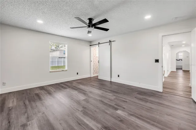 an empty room with wooden floor a ceiling fan and windows