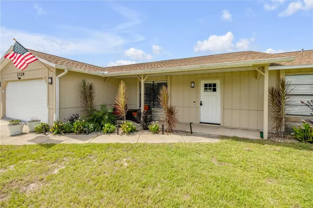 a backyard of a house with table and chairs under an umbrella