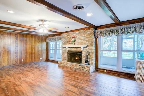 a view of a livingroom with wooden floor a fireplace and window