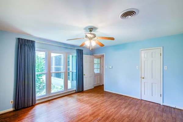 a view of an empty room with window and wooden floor